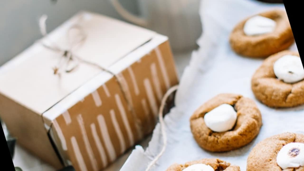 A bunch of sugar cookies next to a gift box on sheet paper