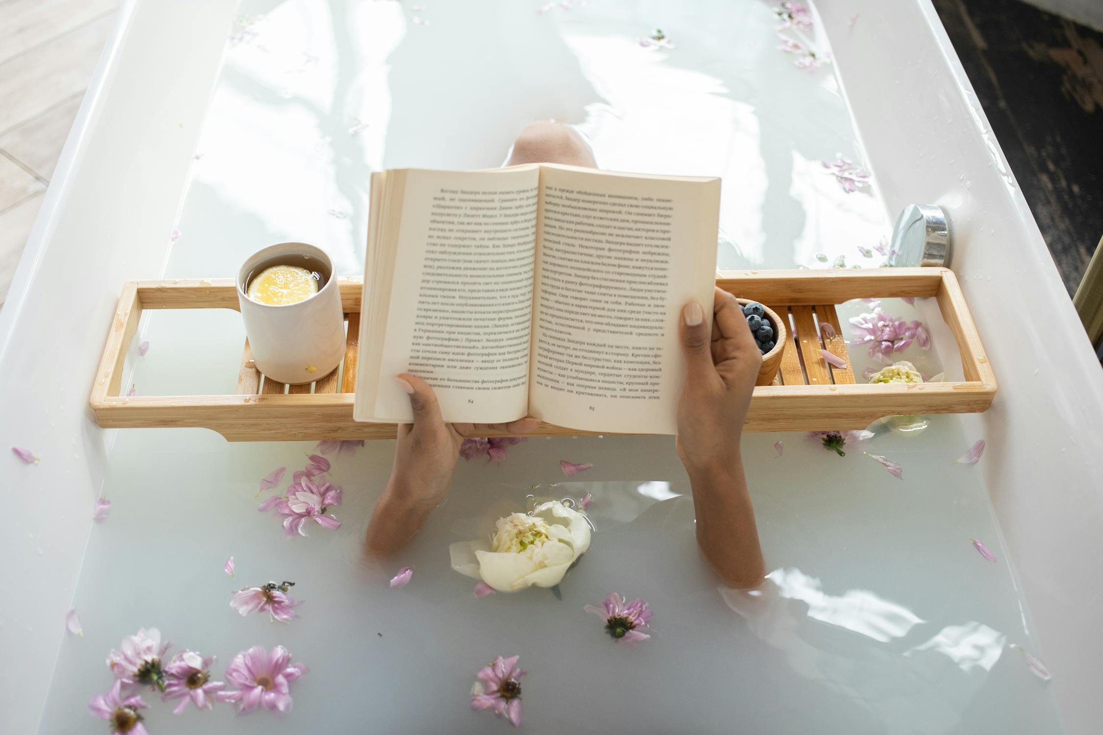 Reading a book in a bath with flowers floating