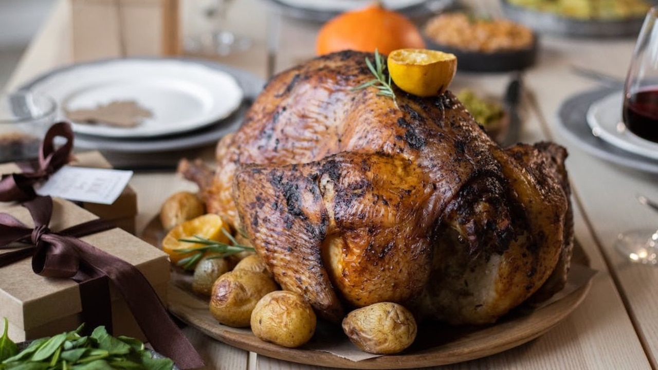 Roasted turkey on a platter with rosemary sprigs and roasted potatoes.