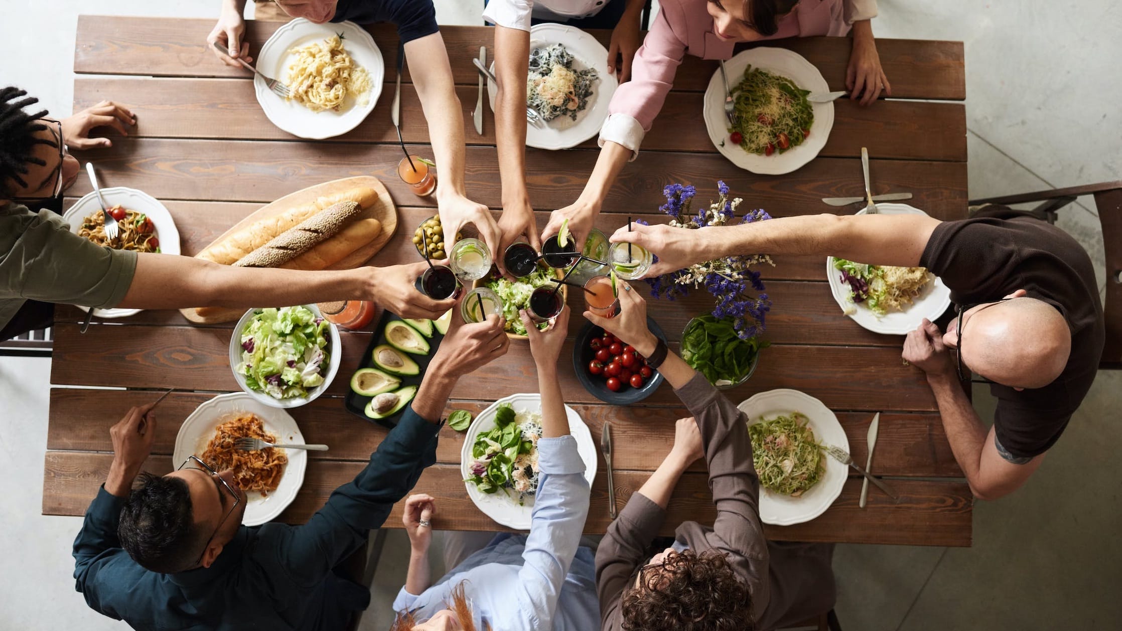Six friends toasting over a table full of festive food