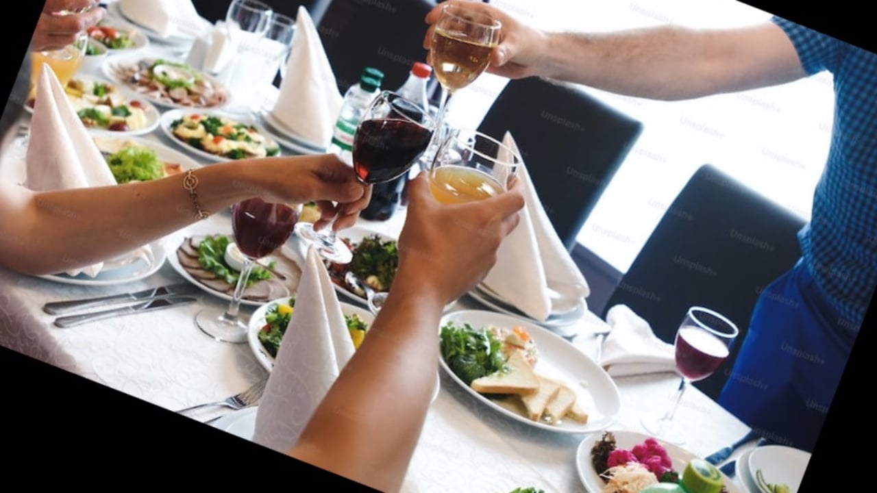 Four arms holding wine glasses and toasting